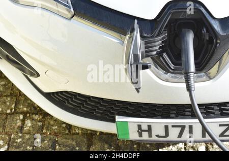 A close up of the front of an electric vehicle or EV charging in a private driveway with the green strip on the number plate visible. Stock Photo