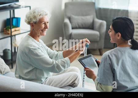 Side view portrait of smiling senior woman talking to female nurse in retirement home, copy space Stock Photo