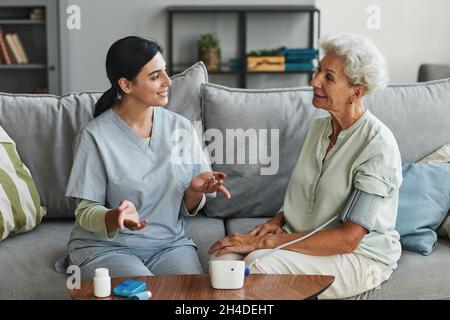 Portrait of smiling senior woman talking to female nurse in retirement home, copy space Stock Photo