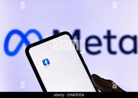 Vilnius Lithuania 01 NOV 2021 Silhouette of man hand holding smartphone with Facebook app shown on white screen in blurred new Facebook name Meta logo Stock Photo