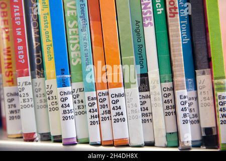 Close-up of books with Library of Congress Classification call numbers on book spines on the shelf in a children’s science section of a public library Stock Photo