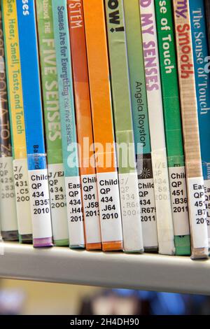 Close-up of books with Library of Congress Classification call numbers on book spines on the shelf in a children’s science section of a public library