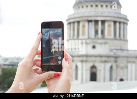 A girl plays PokeŽmon Go with St Paul's Cathedral in the background, London,  in July 25, 2016. UK is the fifth place worldwide where the mobile app is available to download. Stock Photo