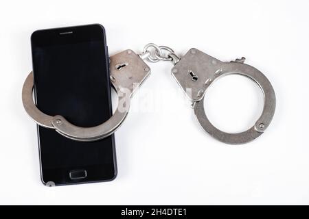 Phone in the Handcuffs on the White Background closeup Stock Photo