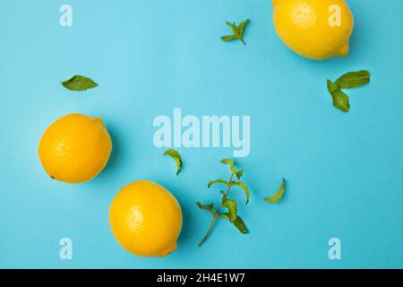 Ripe lemons with mint leaves isolated on bright blue background with copy space for your text. Top view. Flat lay pattern, banner. Frame made of fresh Stock Photo