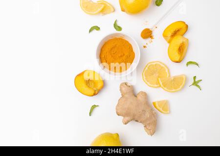 Fresh turmeric, ginger and citrus juice ingredients on a white plate, top view. Natural vitamin drink that protects health from viruses. Stock Photo