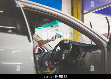 Man specialist installing tinting film on car window. Stock Photo