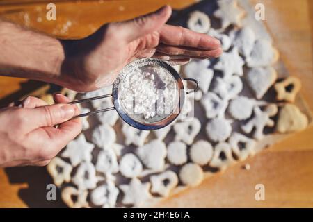 Preparation of Christmas sweets during advent. Powdered sugar falling on Linzer cookies. Stock Photo