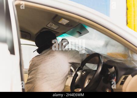 Male specialist applying window tinting film on the car. Stock Photo