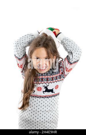 portrait of merry, laughing girl in white knitted Christmas sweater with reindeer taking off gnome Christmas hat from head, isolated on white Stock Photo