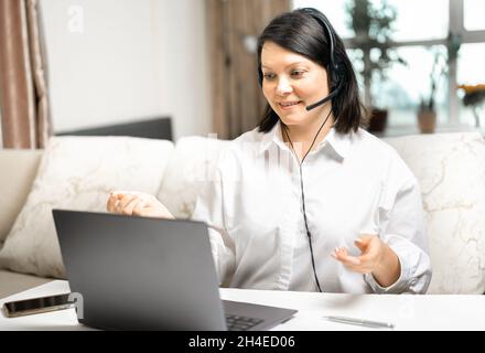 businesswoman using laptop talk to colleagues in video call while smart working from home at living room. Businesswoman entrepreneur works from home a Stock Photo