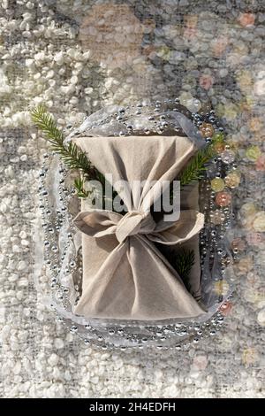 Furoshiki style gift for Christmas or New Year on a white soft cosy background with bokeh. Flat lay with jewelry beads. Stock Photo