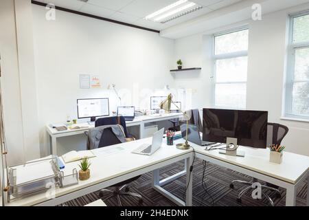 Interior of empty modern office with desks, chairs, laptops and computers Stock Photo