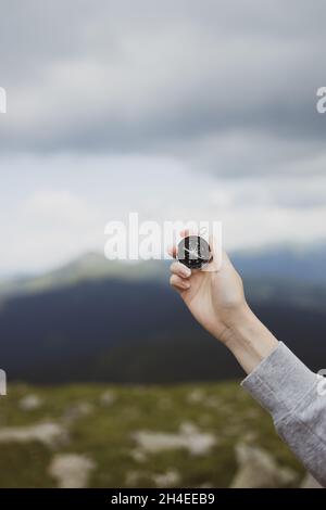 Traveler hand holds compass against beautiful Carpathian mountains view. Horizontal banner with place for text. Stock Photo