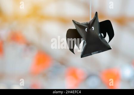 Origami bat made of black paper hanging on a rope for Halloween decorations. Dark paper ghost Halloween party concept origami paper bat. The figure of Stock Photo