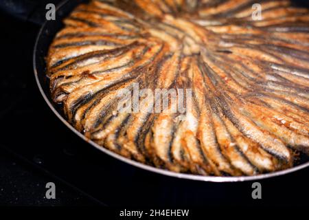 Anchovy in a round teflon pan on the stove Stock Photo