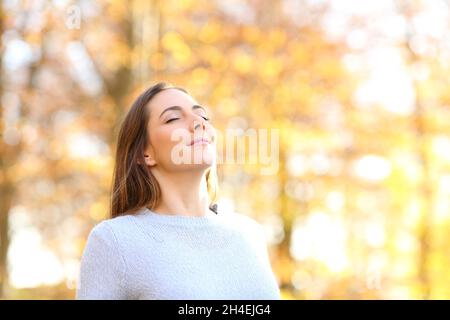 Happy relaxed female breathing fresh air in autumn in a forest Stock Photo