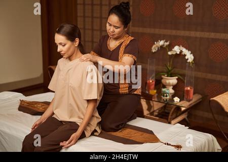 Practitioner palm pressing trigger points on patient shoulders Stock Photo