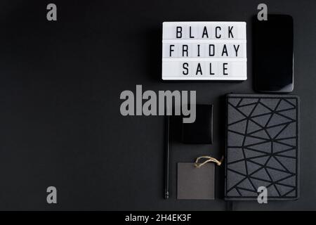 Black Friday online sale concept. Monochromatic flatlay on a dark background. Smartphone and accessories. Stock Photo