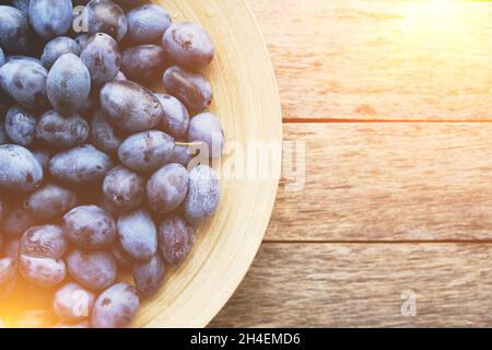 Plate with plums on a rustic wooden background, top view Stock Photo