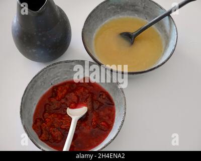 Close up of homemade apple sauce and plum roaster on Nordic earthenware plates, white background. Stock Photo