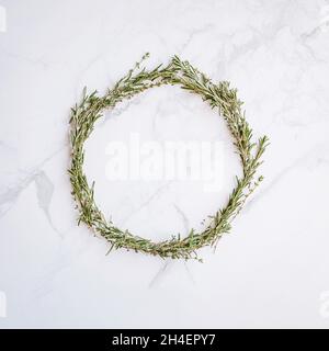 Christmas wreath of rosemary thyme on a white marble surface. Stock Photo