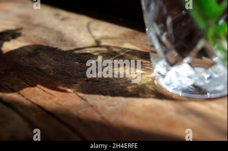 Water in glass with caustic light. Dispersion light. Crystal light and shadow on wooden surface. Stock Photo