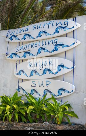 Decorative surfboards with different types of watersports written on each, Diani, Kenya Stock Photo