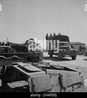 A vintage photo circa May 1943 an allied truck filled with British soldiers of the 8th army passes wrecked German tanks in Porto Farina, Tunisia during World War 2.  Taken at the end of the Battle of Tunis when the Afrika Korps finally surrendered to the allies. Stock Photo