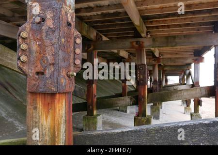 Underneath of wooden pier showing rusty nuts and bolts and staining Stock Photo