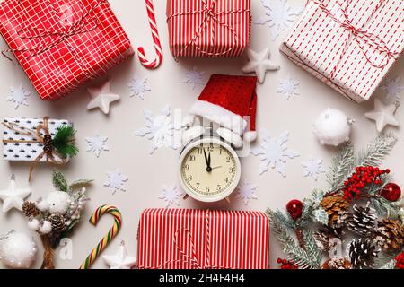 New Year's winter composition. Alarm clock santa hat Christmas boxes with gift fir branches on a white background. Frame border flat lay top view Stock Photo