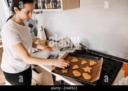 Woman cooking gingerbread. Christmas homemade gingerbread biscuit at baking pan on home kitchen. Cooking at home, Gingerbread making process Stock Photo