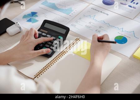 Hands of marketing manager calculating income after analyzing data in various reports