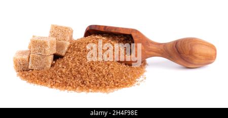 Brown sugar in wooden scoop, isolated on white background. Heap of cane sugar crystals and sugar cubes. Stock Photo