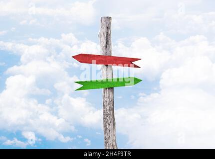 Two colored wooden arrows pointers red and green. Blue sky background with clouds. Stock Photo