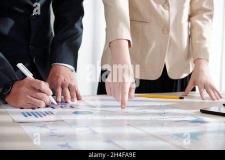 Managers of marketing department working on new strategy and analyzing data in various reports Stock Photo