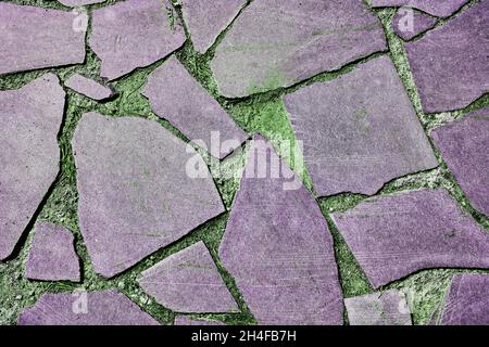 Gray old stone pavement on a background of green grass. Seamless Texture. Texture of a stone road. High quality photo Stock Photo