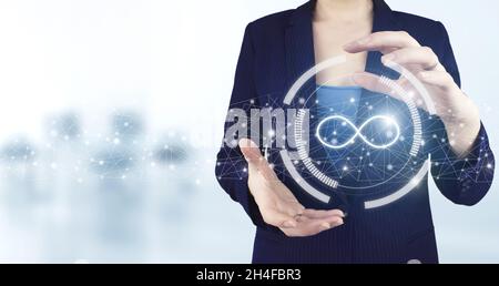 Infinite concept. Two hand holding virtual holographic infinity icon with light blurred background. The concept of unlimited Internet Stock Photo