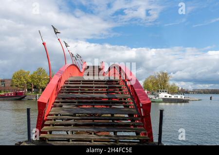 Amsterdam, The Netherlands-May 2021: Low angle view of the wooden steps of the red metal snake like Pythonbrug which is a footbridge crossing over the Stock Photo