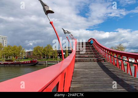 Amsterdam, The Netherlands-May 2021: Low angle view of the wooden steps of the red metal snake like Pythonbrug which is a footbridge crossing over the Stock Photo