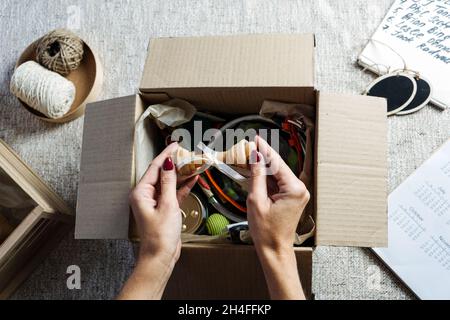 Female hands put stuff in Pet Subscription Box for Dogs and Cats. Subscription pet box with Organic Treats, Fun Toy, Bully Sticks, All-Natural Chews Stock Photo