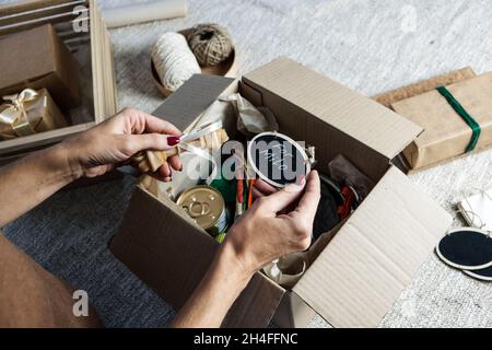 Female hands put stuff in Pet Subscription Box for Dogs and Cats. Subscription pet box with Organic Treats, Fun Toy, Bully Sticks, All-Natural Chews Stock Photo