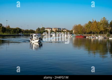 Boat passing through the city.  Small boat moving on the lake, houses in the background. Stock Photo