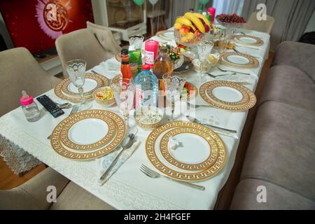 Empty plate , gold set on wooden white table . Beautifully decorated table with gold plates, linen napkin , spoon, fork . Stock Photo