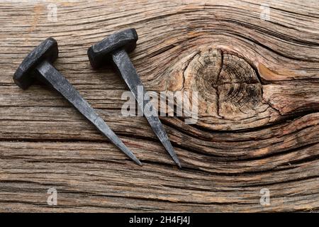 two iron forged nails on a wooden background Stock Photo