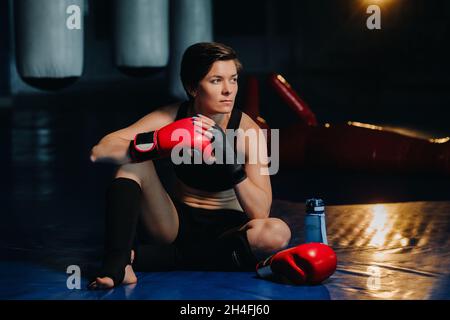 portrait of a female boxer in red gloves in the gym after training. Stock Photo