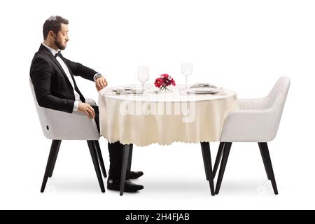 Disappointed man sitting alone at a restaurant table and checking time isolated on white background Stock Photo