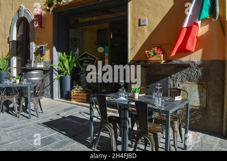 Tables and chairs on the sidewalk outside a typical Tuscan bistrot in the medieval village of Castagneto Carducci, Livorno, Tuscany, Italy Stock Photo