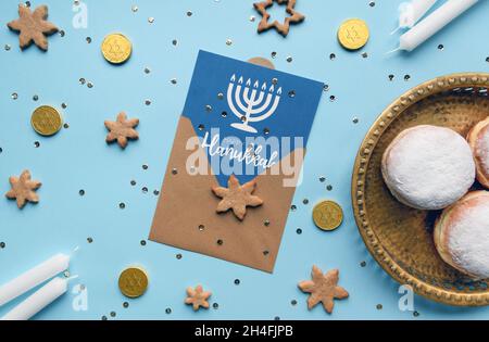 Overhead photo of Hanukkah flat lay with jelly donuts, holiday card and white candles on blue background Stock Photo