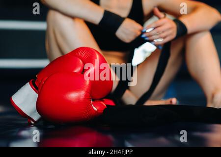 Close-up of red boxing gloves on the floor of a blue boxing ring. Stock Photo